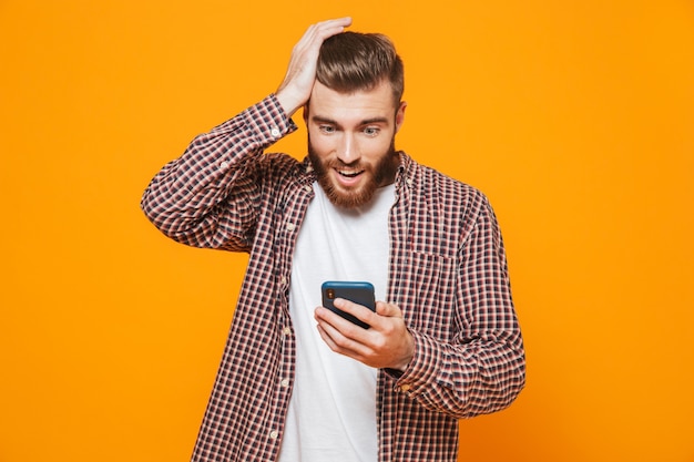 Retrato de um jovem confuso, vestindo roupas casuais, usando um celular