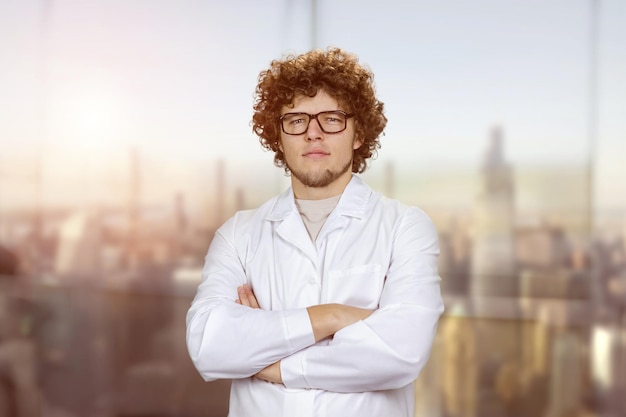 Foto retrato de um jovem cozinheiro de uniforme branco usando óculos borrada paisagem urbana no fundo