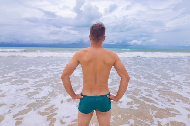 Retrato de um jovem de pé ao ar livre olhando para o mar