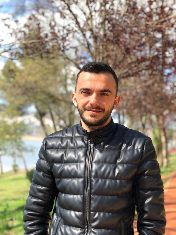 Foto retrato de um jovem de pé contra as árvores no parque
