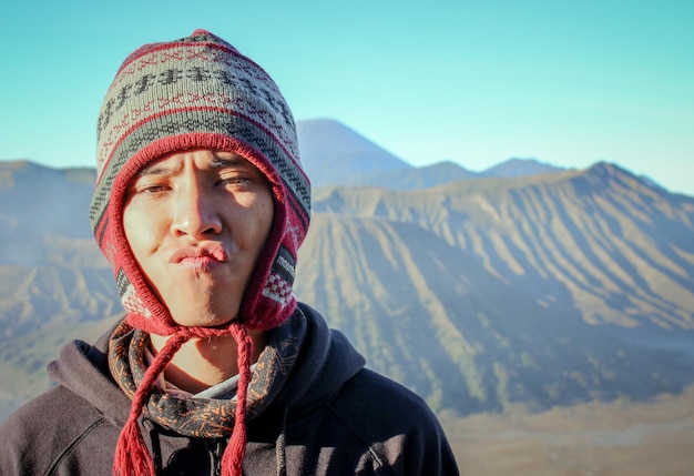 Retrato de um jovem de pé contra as montanhas durante o inverno