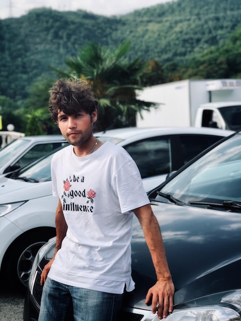Retrato de um jovem de pé contra carros