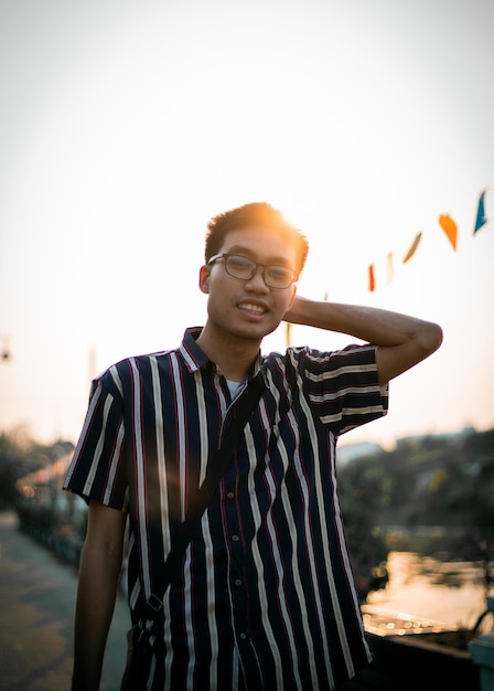 Foto retrato de um jovem de pé contra o céu claro durante o pôr-do-sol