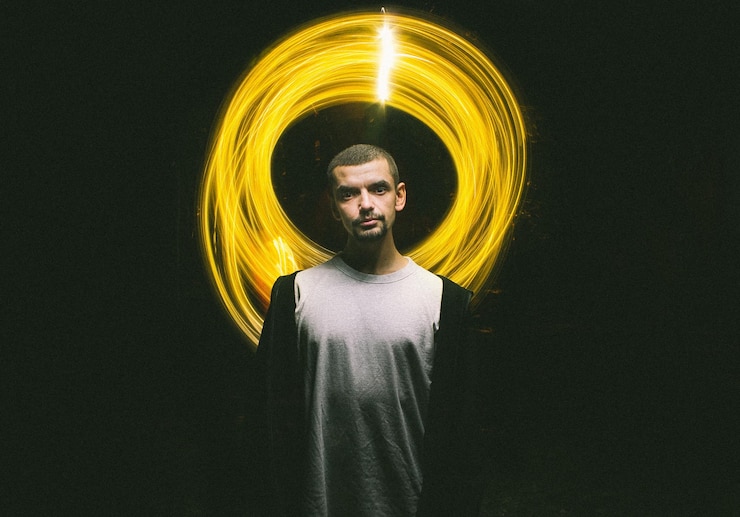 Foto retrato de um jovem de pé contra uma iluminação giratória
