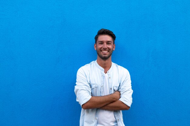 Foto retrato de um jovem de pé contra uma parede azul