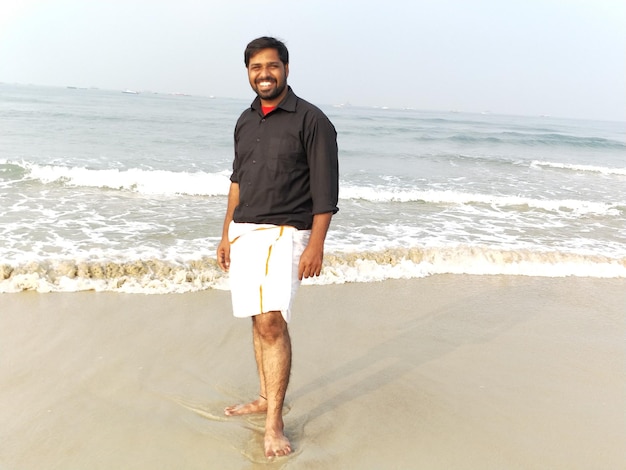 Foto retrato de um jovem de pé na praia