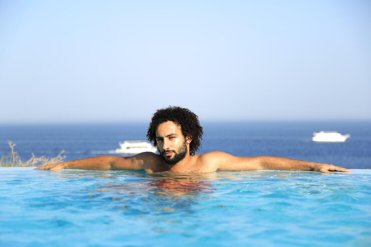 Foto retrato de um jovem descansando em uma piscina infinita contra um céu claro