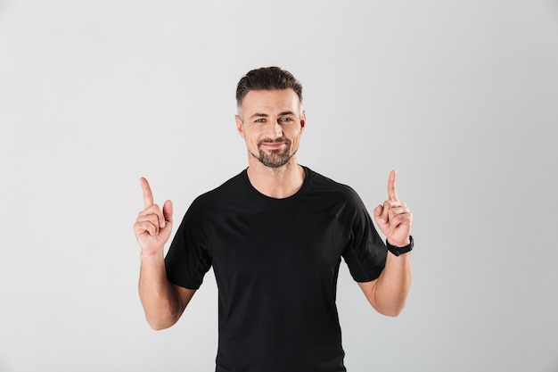 Retrato de um jovem desportista sorridente apontando os dedos para cima