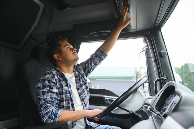 Foto retrato de um jovem e bonito caminhoneiro indiano o conceito de logística e transporte de mercadorias