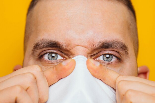 Retrato de um jovem em um respirador closeup em uma proteção respiratória amarela contra o vírus. O conceito de coronavírus.