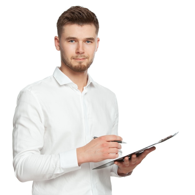 Retrato de um jovem em uma camisa branca com um caderno e uma caneta nas mãos se comunica com o cliente, faz anotações e olha para o quadro. A figura é isolada em um fundo branco.