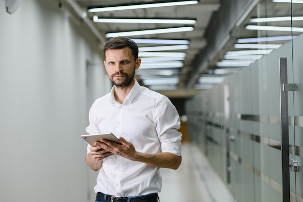 Retrato de um jovem em uma camisa branca no escritório, o gerente do escritório está segurando uma foto de alta qualidade de laptop