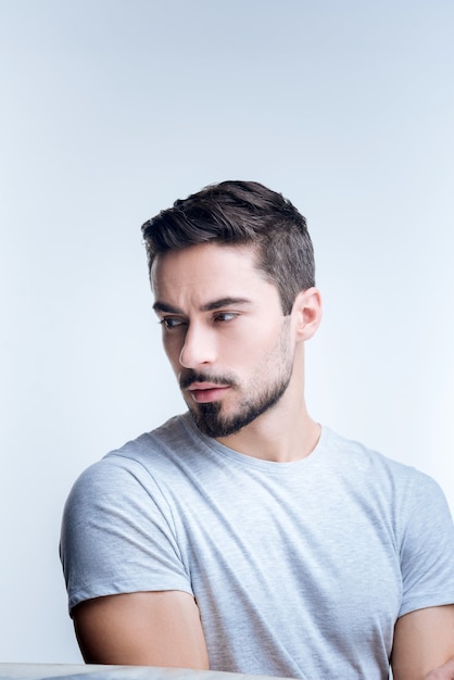 retrato de um jovem em uma camiseta cinza posando contra uma parede branca