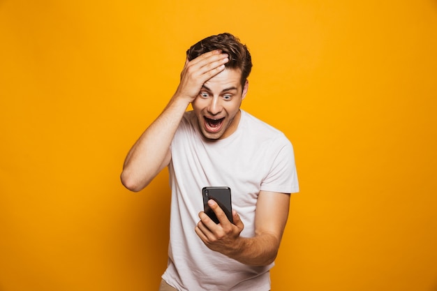 Retrato de um jovem emocionado olhando para o celular