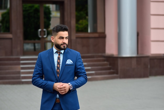 Retrato de um jovem empresário árabe bonito olhando para longe pensativamente posando ao ar livre