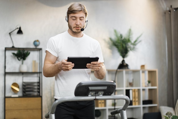 Retrato de um jovem empresário bonito, ativo e dinâmico, com fone de ouvido e tablet fazendo esporte fitness