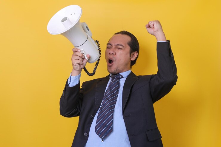Foto retrato de um jovem empresário bonito de terno está gritando e segurando o megafone isolado sobre y