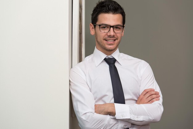 Retrato de um jovem empresário bonito e confiante em pé com os braços cruzados