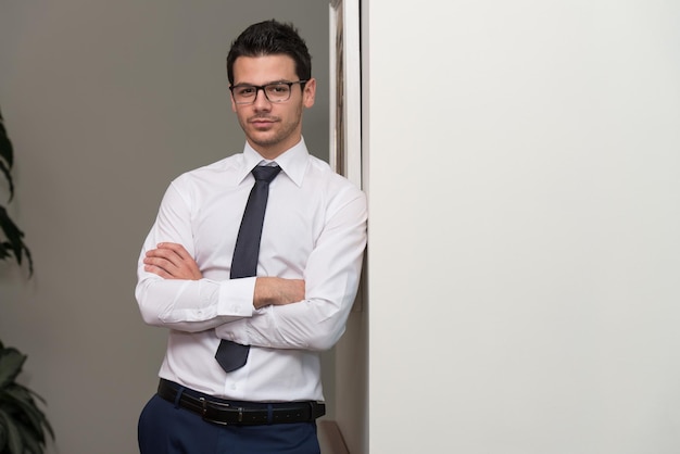 Retrato de um jovem empresário bonito e confiante em pé com os braços cruzados