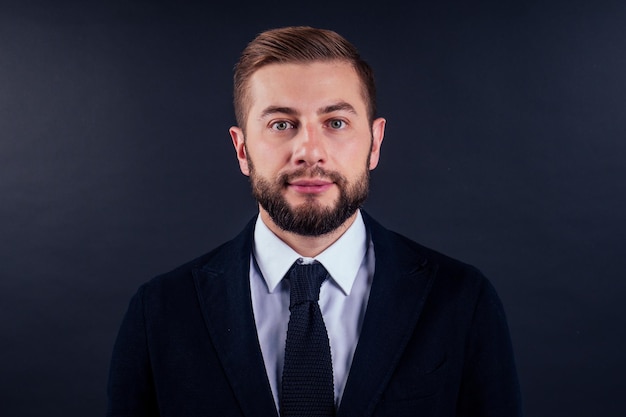 Retrato de um jovem empresário bonito segurando o cartão de crédito sobre fundo preto