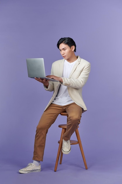 Retrato de um jovem empresário bonito sorridente segurando e usando um laptop