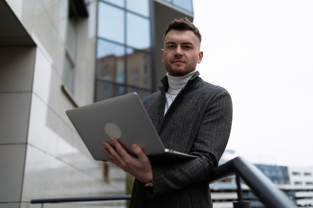 Retrato de um jovem empresário com um laptop fora do escritório