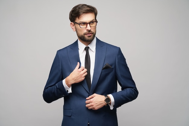 Retrato de um jovem empresário elegante bonito usando óculos sobre parede cinza