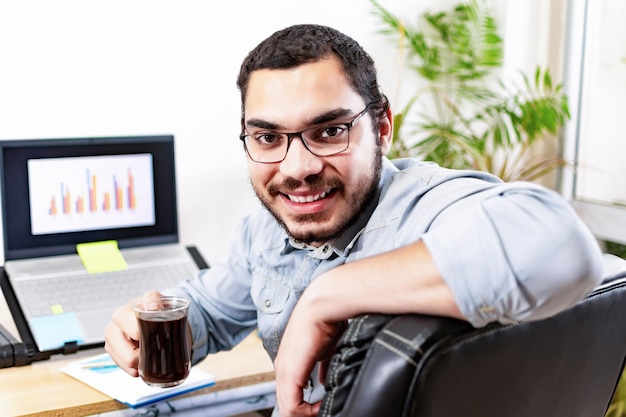 Retrato de um jovem empresário feliz e bem-sucedido, empresário freelancer, sorridente, trabalhando olhando para trás