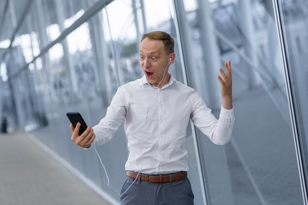 Retrato de um jovem empresário feliz em fones de ouvido. O homem recebeu boas notícias.