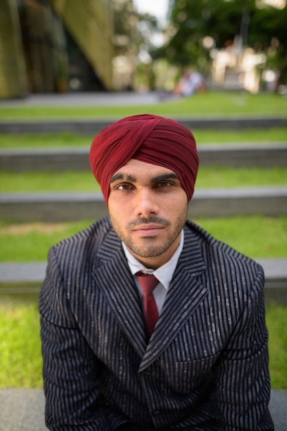 Foto retrato de um jovem empresário sikh indiano usando turbante enquanto explora a cidade de bangkok, tailândia