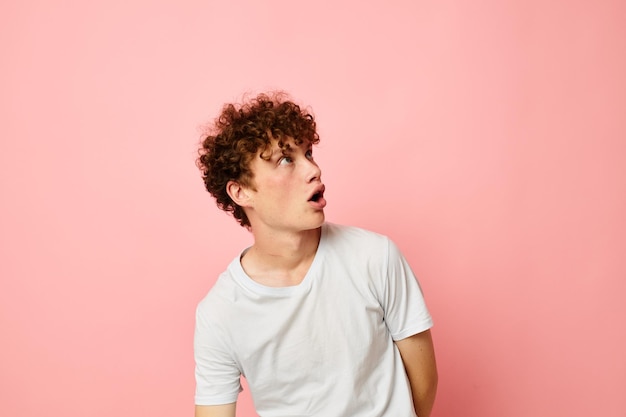 Retrato de um jovem encaracolado com roupas de verão camiseta branca posando estilo de vida inalterado