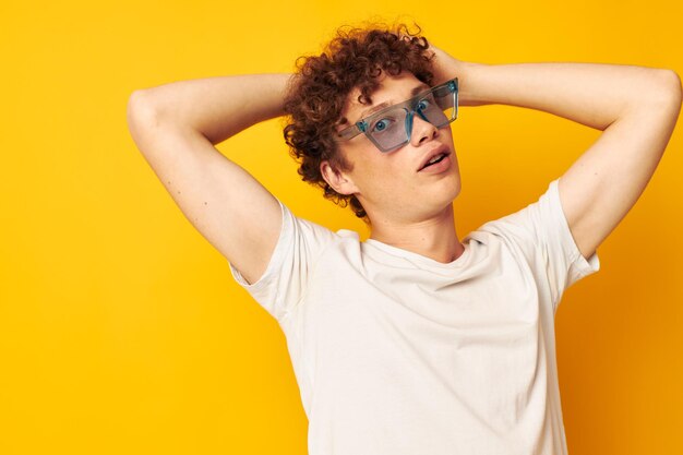 Retrato de um jovem encaracolado em uma camiseta branca óculos de moda azul isolado fundo inalterado