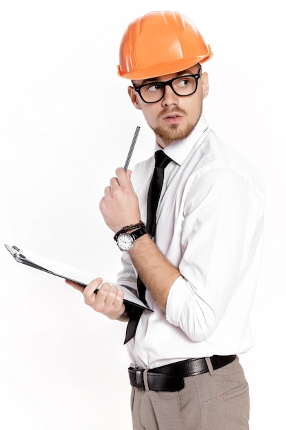 Retrato de um jovem engenheiro civil em um capacete laranja com uma pasta em um fundo branco