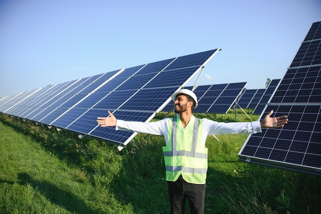 Retrato de um jovem engenheiro indiano de pé perto de painéis solares com fundo de céu azul claro Habilidades de energia renovável e limpa na Índia