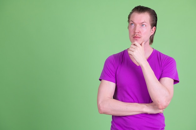 Retrato de um jovem escandinavo bonito vestindo uma camisa roxa contra o chroma key ou uma parede verde