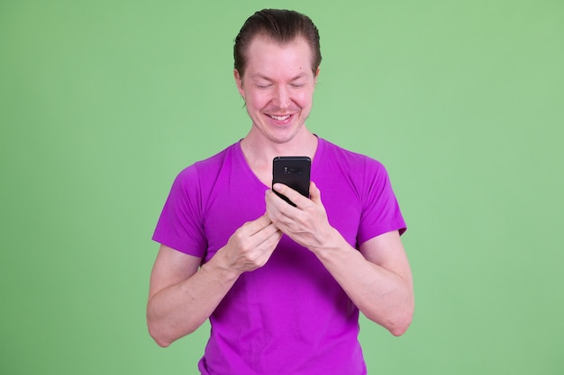 Retrato de um jovem escandinavo bonito vestindo uma camisa roxa contra o chroma key ou uma parede verde