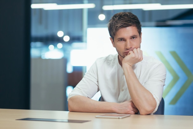 Retrato de um jovem estudante do sexo masculino Sério se preparando para o exame estudando online remotamente Sentado à mesa com um laptop cansado segurando a cabeça na mão