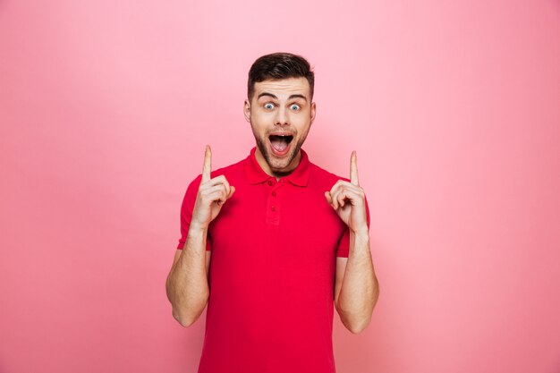 Retrato de um jovem feliz, apontando os dedos para cima