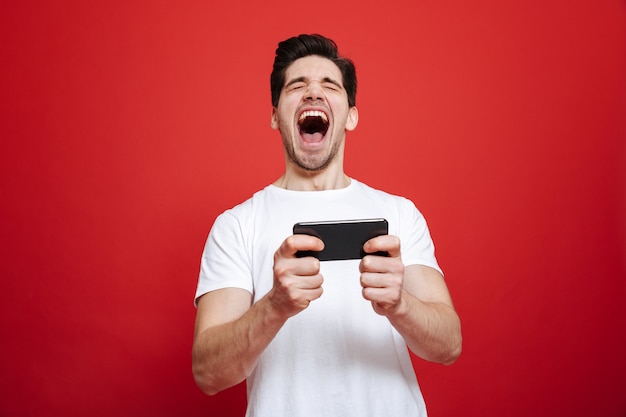 Retrato de um jovem feliz em camiseta branca comemorando