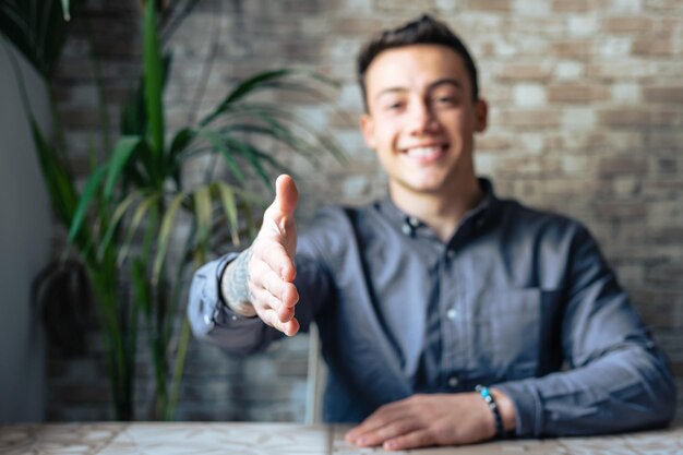 Retrato de um jovem feliz que estende a mão para convidar o espectador a juntar-se à equipa empresarial. um gerente capaz e amigável que olha para a câmara estende a mão para dar as boas-vindas a um novo cliente ou colega.