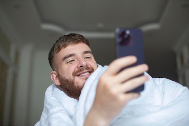 Retrato de um jovem feliz, um cara feliz e alegre está olhando para a tela de seu celular