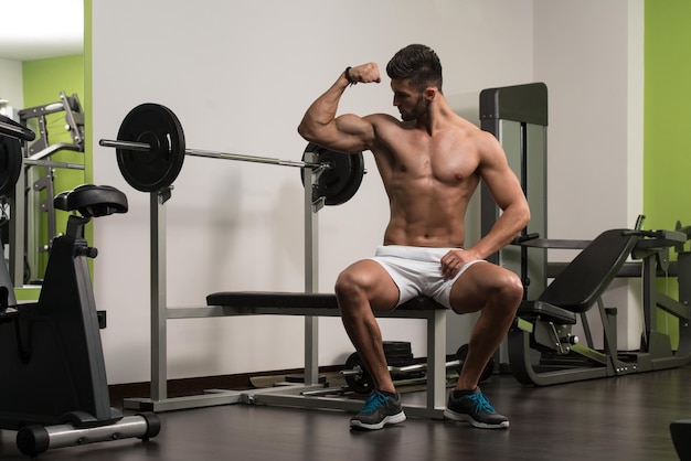 Retrato de um jovem fisicamente apto descansando no banco e mostrando seu corpo bem treinado