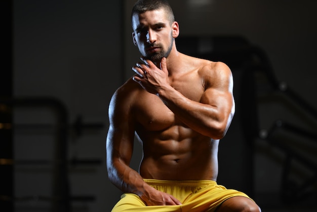 Retrato de um jovem fisicamente apto mostrando seu corpo bem treinado musculoso fisiculturista fitness modelo posando após exercícios