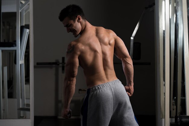 Retrato de um jovem fisicamente apto mostrando seu corpo bem treinado musculoso fisiculturista fitness modelo posando após exercícios