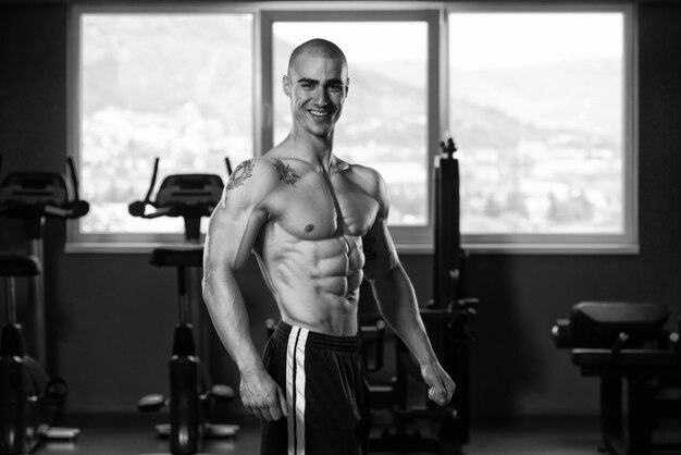 Retrato de um jovem fisicamente apto mostrando seu corpo bem treinado musculoso fisiculturista fitness modelo posando após exercícios