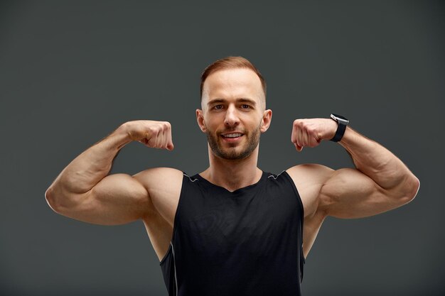 Foto retrato de um jovem flexionando os músculos contra um fundo preto