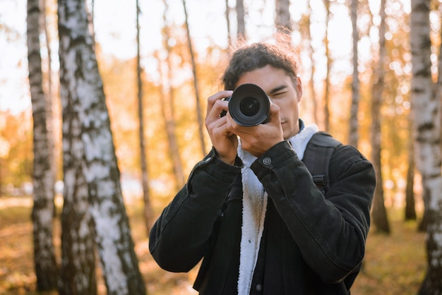 Retrato de um jovem fotógrafo masculino fotografar paisagens na floresta de outono