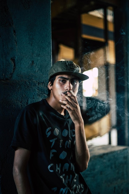Retrato de um jovem fumando um cigarro contra a parede