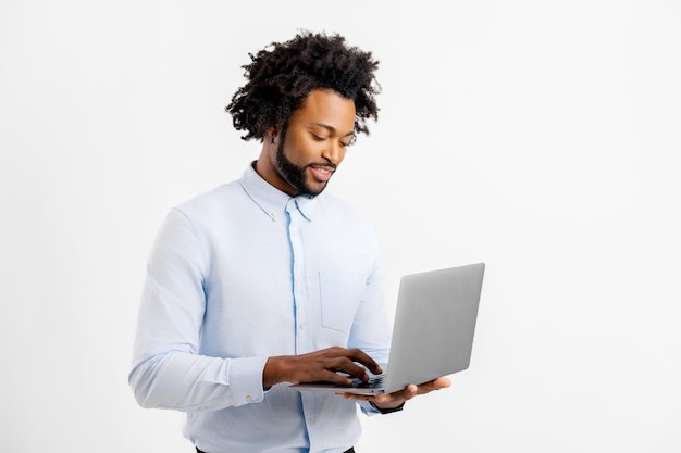 Retrato de um jovem funcionário de escritório isolado em branco segurando um laptop digitando mensagens conversando on-line desfrutando de uma nova aplicação de computador navegando na web