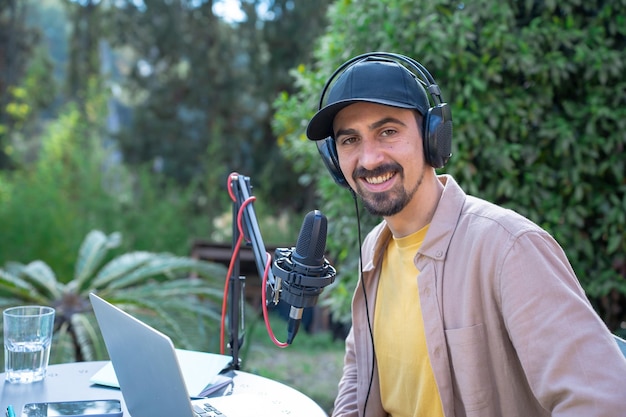 Foto retrato de um jovem gravando um podcast olhando para a câmera ao ar livre na primavera